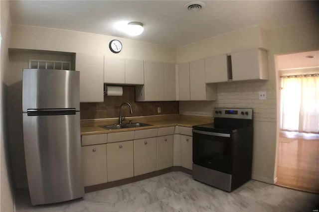 kitchen with stainless steel appliances, a sink, visible vents, light countertops, and backsplash