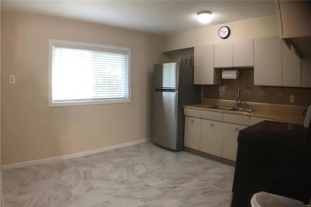 kitchen featuring a sink, white cabinetry, light countertops, range, and freestanding refrigerator