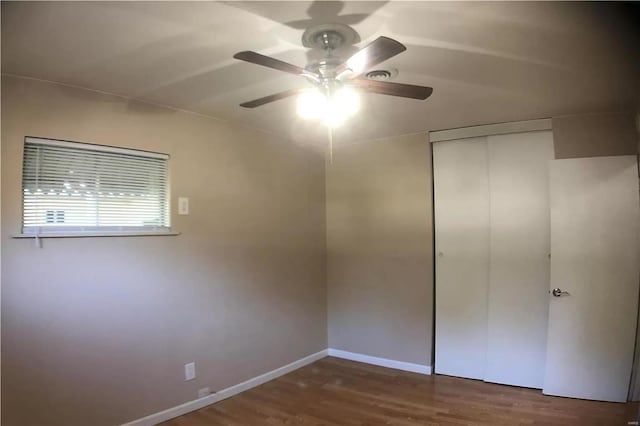 unfurnished bedroom featuring dark wood-style floors, a closet, ceiling fan, and baseboards