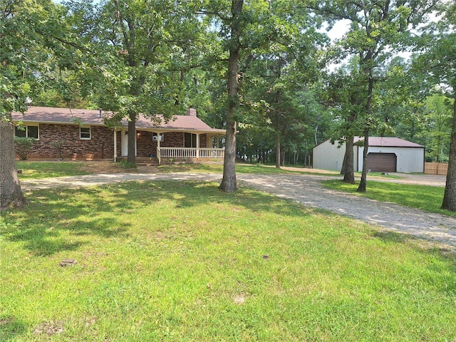 ranch-style home featuring an outbuilding, a porch, a garage, and a front yard