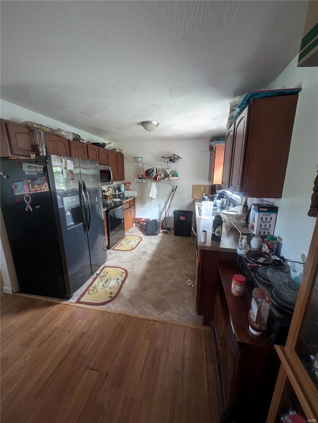 kitchen with light hardwood / wood-style floors, electric range oven, and black fridge