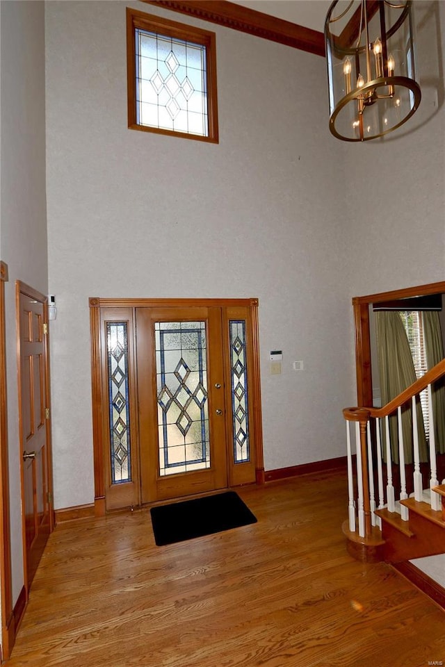 entrance foyer with light hardwood / wood-style flooring, a chandelier, and a high ceiling