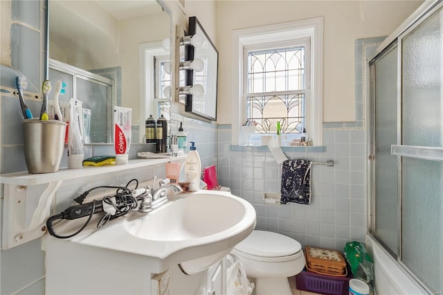 full bathroom with shower / bath combination with glass door, vanity, toilet, and tile walls