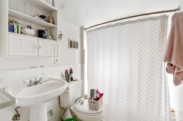 bathroom with sink, a shower with shower curtain, tile walls, and toilet