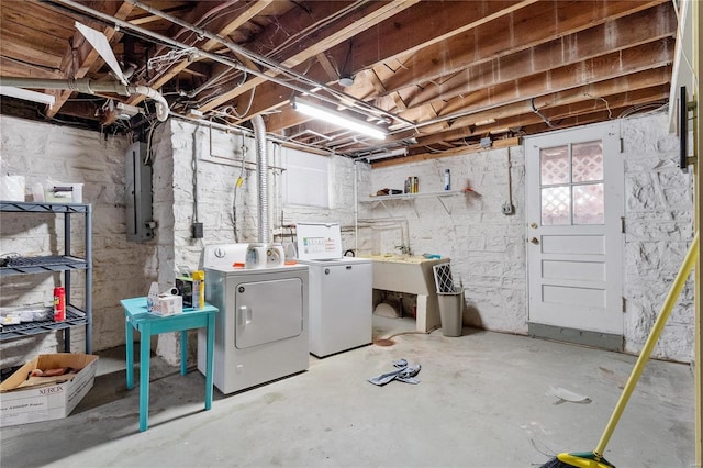 basement featuring electric panel and washing machine and clothes dryer