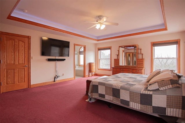 carpeted bedroom featuring ensuite bathroom, a raised ceiling, multiple windows, and ceiling fan