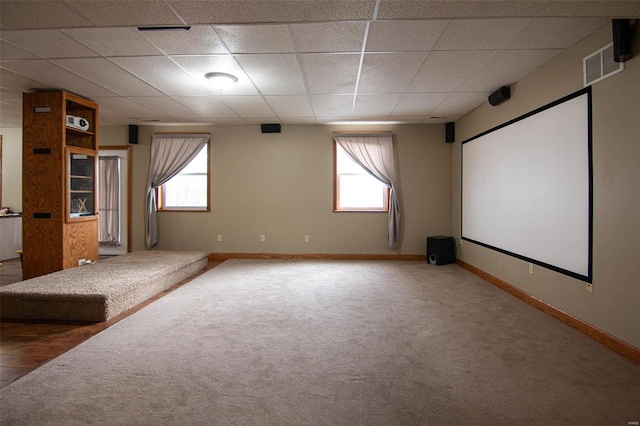 carpeted home theater room featuring a paneled ceiling and a wealth of natural light