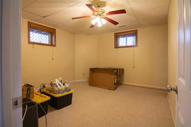 basement with carpet flooring, a drop ceiling, and plenty of natural light