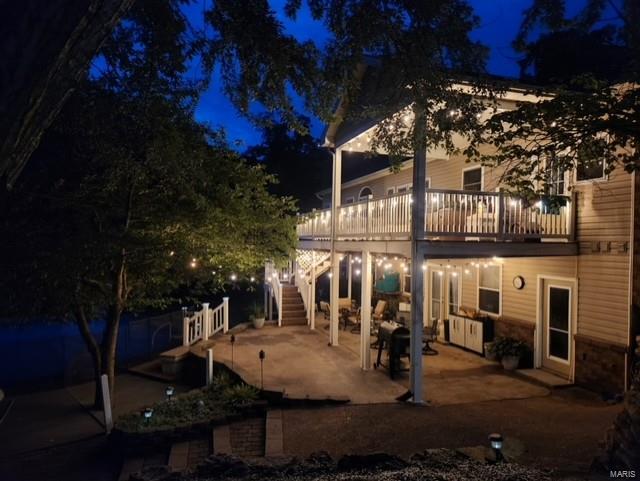 back house at twilight featuring a patio area and a balcony