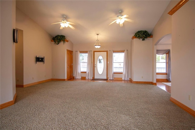 entryway with a ceiling fan, arched walkways, vaulted ceiling, and light carpet