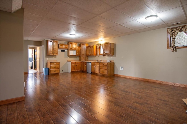 interior space with a sink, baseboards, a drop ceiling, and dark wood-style floors