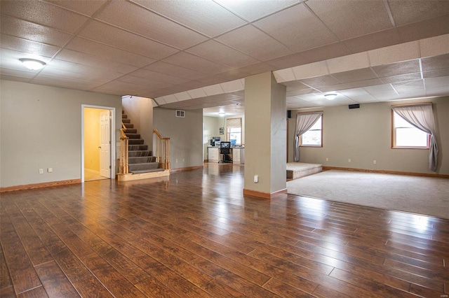 basement with stairs, a drop ceiling, and wood finished floors