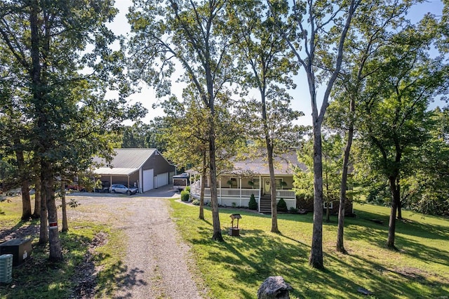 view of front of home featuring a porch, driveway, an outdoor structure, a front lawn, and an attached garage
