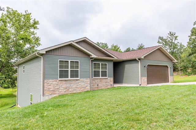 view of front of property featuring stone siding, a front lawn, and a garage