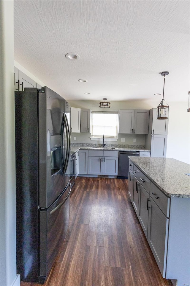 kitchen with decorative light fixtures, stainless steel dishwasher, dark hardwood / wood-style flooring, black fridge with ice dispenser, and gray cabinetry