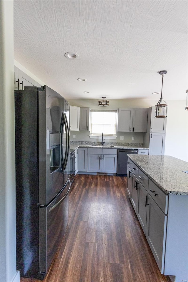 kitchen featuring stainless steel appliances, gray cabinets, a sink, dark wood-type flooring, and light stone countertops