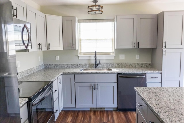kitchen with light stone counters, a sink, dark wood finished floors, appliances with stainless steel finishes, and visible vents