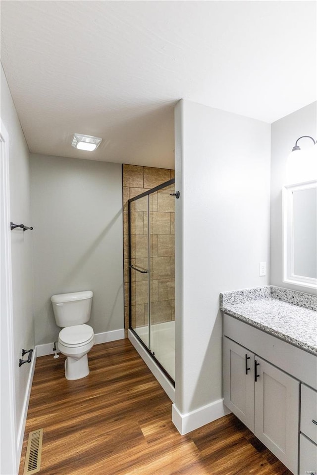 bathroom with a shower stall, wood finished floors, visible vents, toilet, and baseboards
