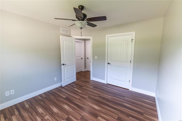unfurnished bedroom featuring dark wood-style floors, baseboards, a ceiling fan, and visible vents