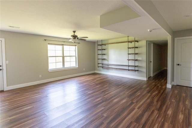 empty room with visible vents, baseboards, ceiling fan, and dark wood-style floors