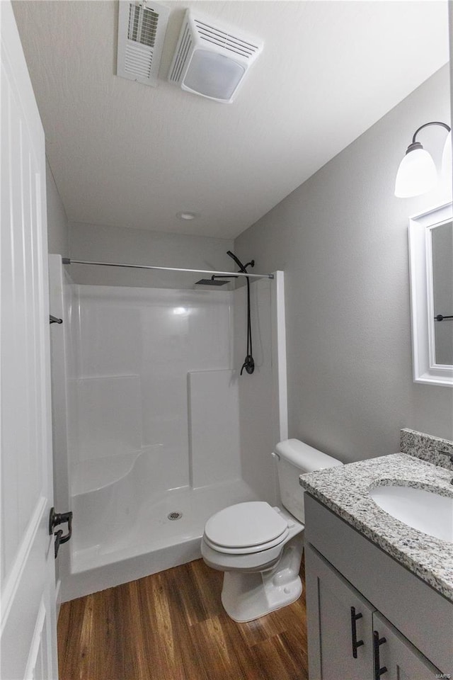 bathroom featuring walk in shower, wood-type flooring, toilet, and vanity