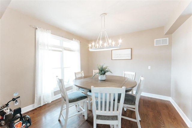 dining room with dark wood-type flooring and a chandelier