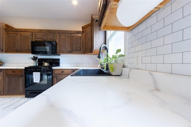 kitchen featuring tasteful backsplash, dark brown cabinetry, sink, and black appliances