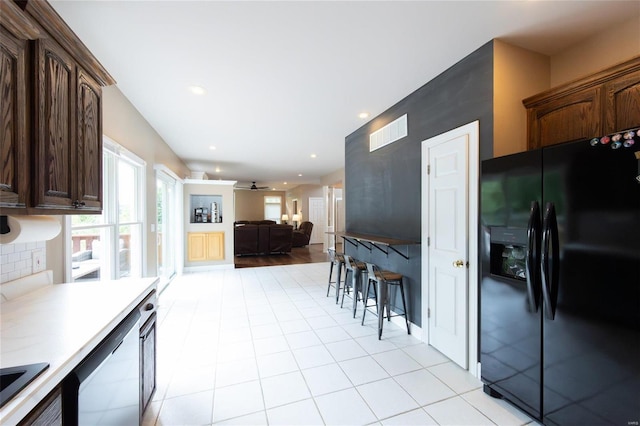 kitchen with backsplash, black fridge with ice dispenser, dark brown cabinets, and ceiling fan