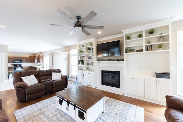 living room featuring ceiling fan, a fireplace, and light hardwood / wood-style floors