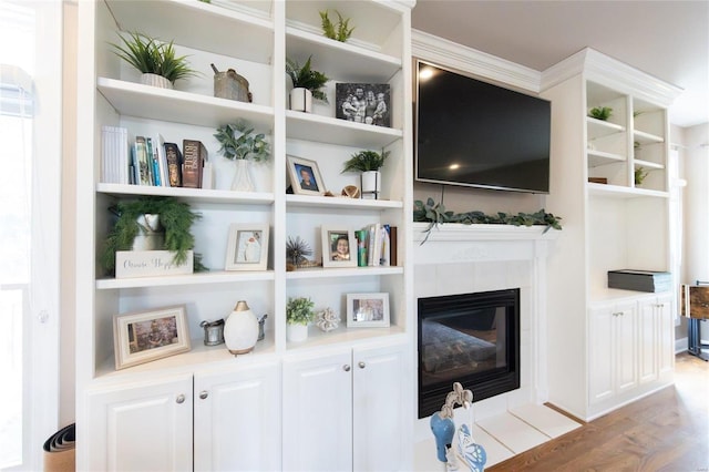 interior space with hardwood / wood-style flooring, a tile fireplace, and built in shelves