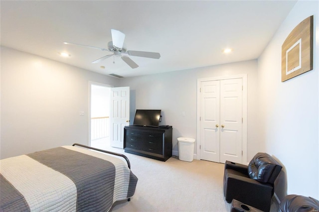 bedroom featuring light carpet, ceiling fan, and a closet