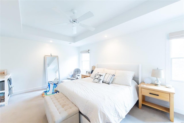 carpeted bedroom featuring a tray ceiling and ceiling fan