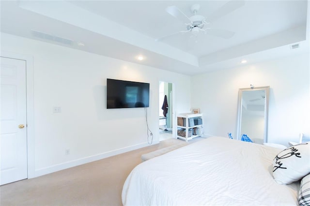 carpeted bedroom with ceiling fan and a tray ceiling