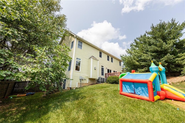 back of property featuring a playground, a yard, and central AC