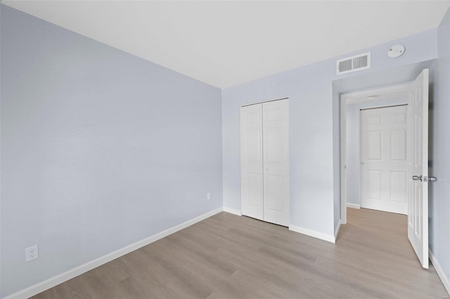 unfurnished bedroom with light hardwood / wood-style flooring and a closet