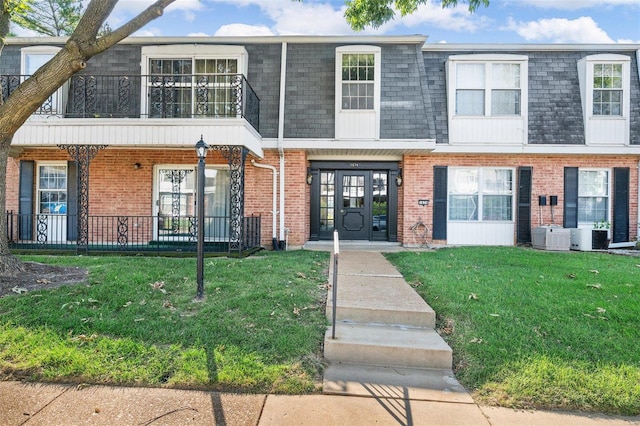 townhome / multi-family property with a balcony, cooling unit, and a front yard