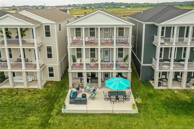 back of property with a patio, a balcony, and a lawn