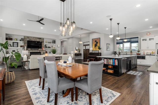 dining area with dark hardwood / wood-style floors, built in features, ceiling fan, sink, and a fireplace