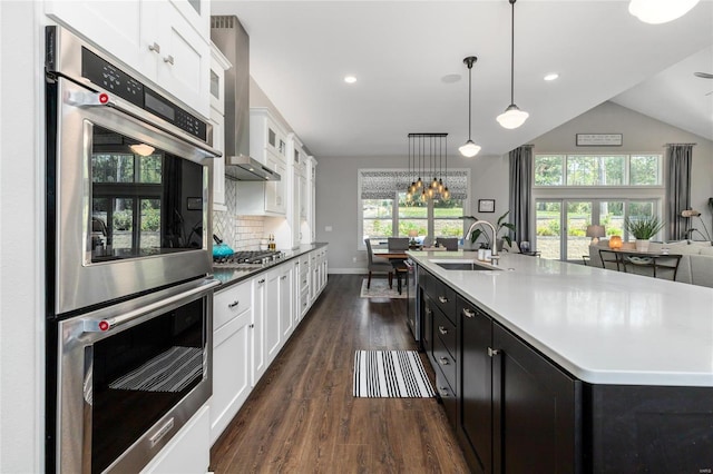 kitchen with dark hardwood / wood-style floors, hanging light fixtures, backsplash, stainless steel appliances, and sink