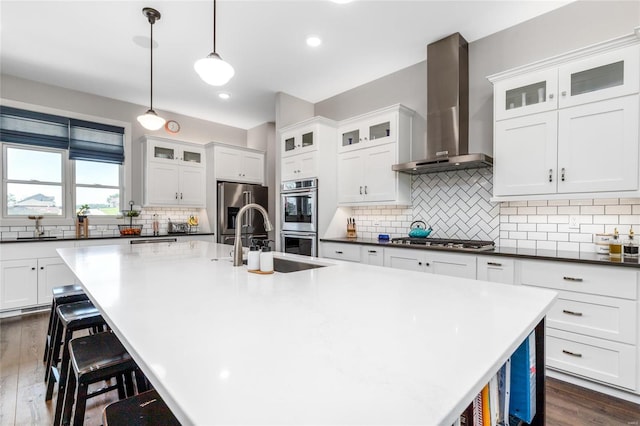 kitchen with decorative backsplash, wall chimney range hood, dark hardwood / wood-style floors, and appliances with stainless steel finishes