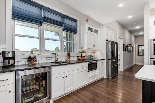 kitchen featuring tasteful backsplash, dark hardwood / wood-style floors, appliances with stainless steel finishes, wine cooler, and sink