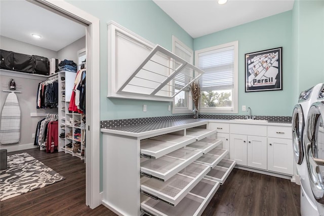 clothes washing area featuring washer and clothes dryer, dark hardwood / wood-style flooring, cabinets, and sink