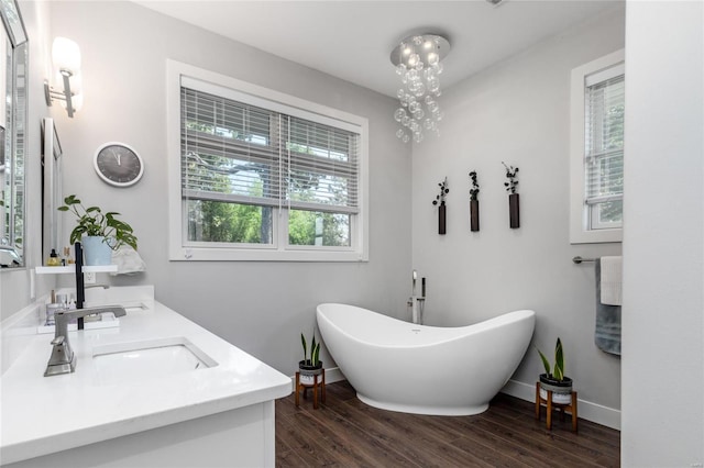 bathroom with hardwood / wood-style floors, a tub to relax in, double vanity, and a chandelier