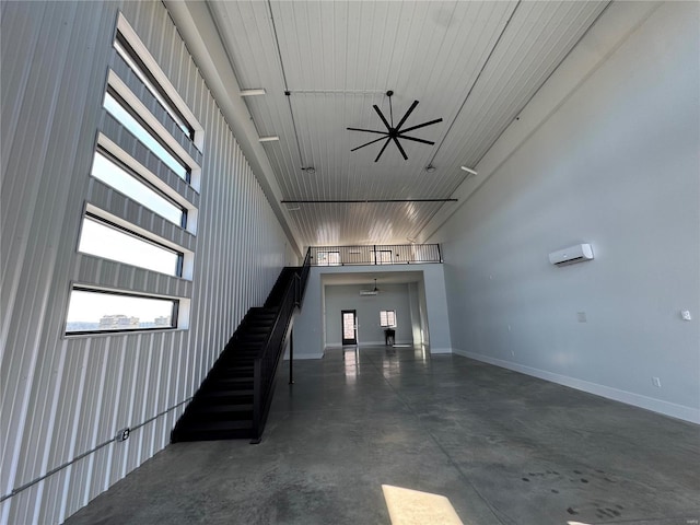 stairs with ceiling fan, a towering ceiling, and concrete floors