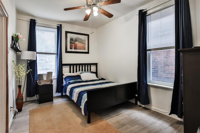 bedroom with multiple windows, light wood-type flooring, and ceiling fan