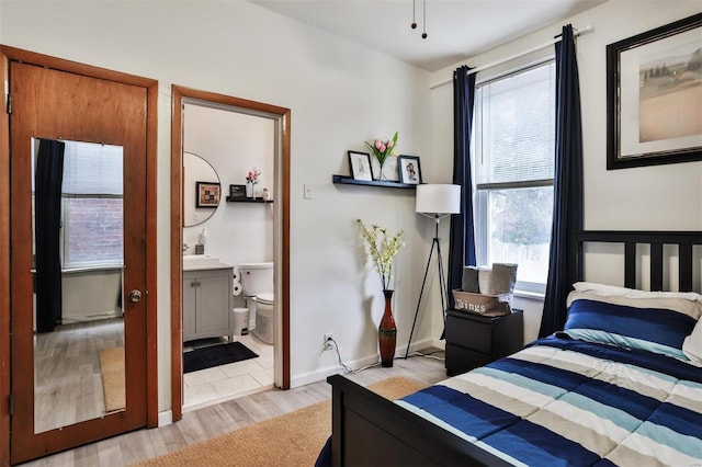 bedroom featuring ensuite bath, multiple windows, and light hardwood / wood-style floors