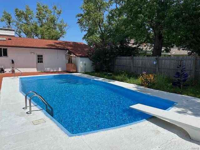 view of pool with a diving board and a patio area