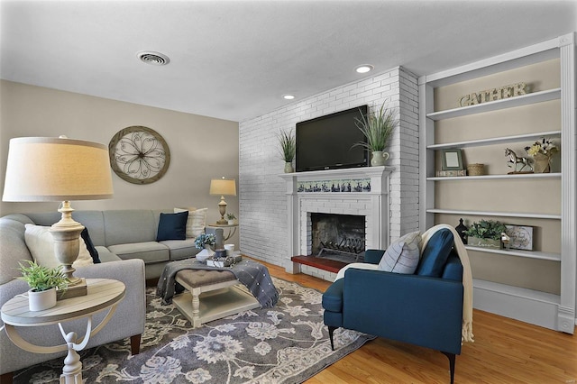 living room featuring wood-type flooring and a brick fireplace