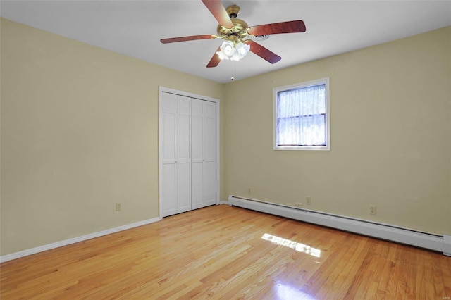 unfurnished bedroom with ceiling fan, a closet, light hardwood / wood-style flooring, and baseboard heating