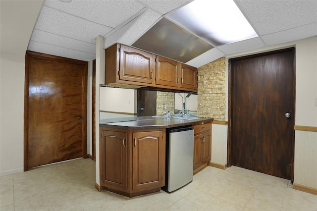 kitchen with dishwasher, a drop ceiling, and vaulted ceiling